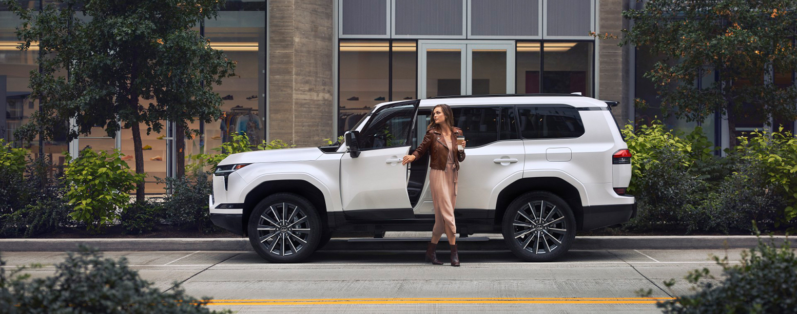 2025 Lexus GX | Woman walking out of her white 2025 Lexus GX with coffee