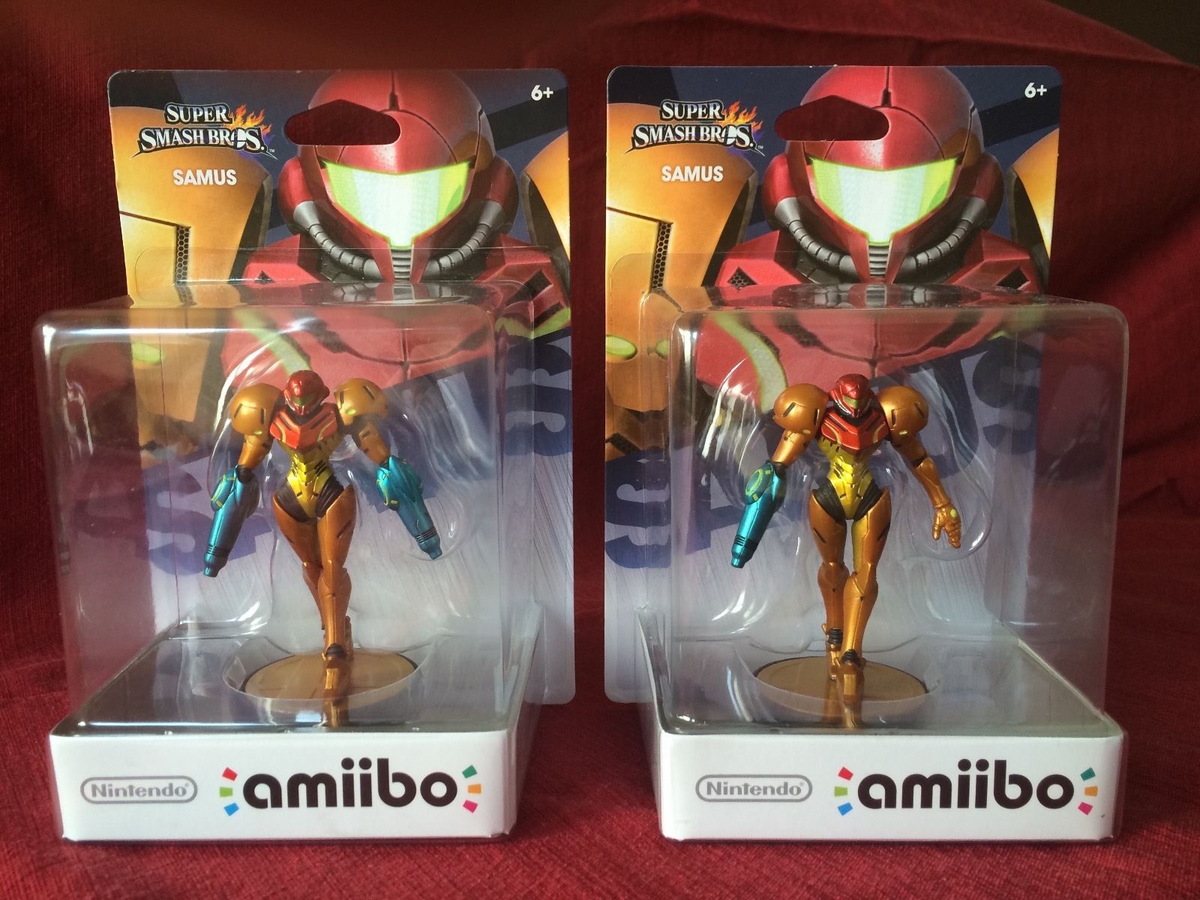 Defective Samus amiibo with arm cannons on both arms next to a normal Samus amiibo for comparison.