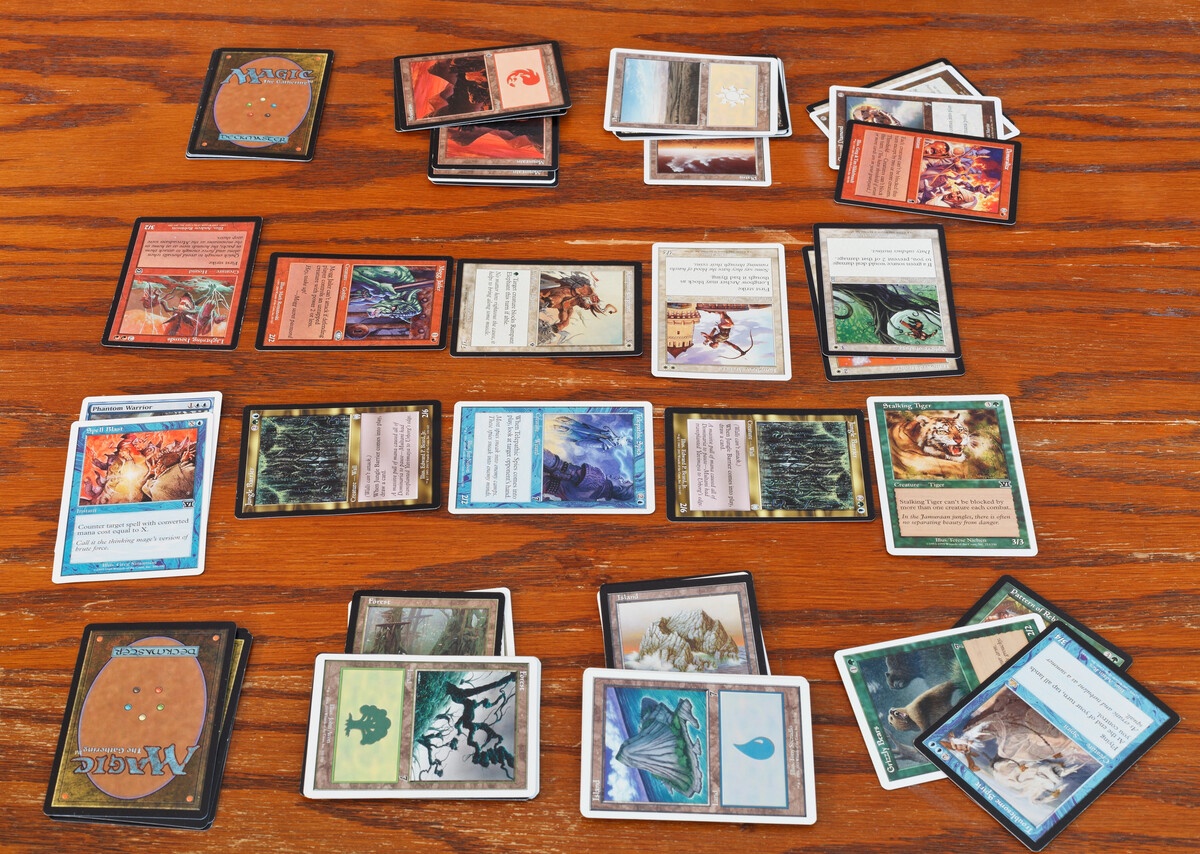 MTG card collection sorted into piles by color on a wooden table