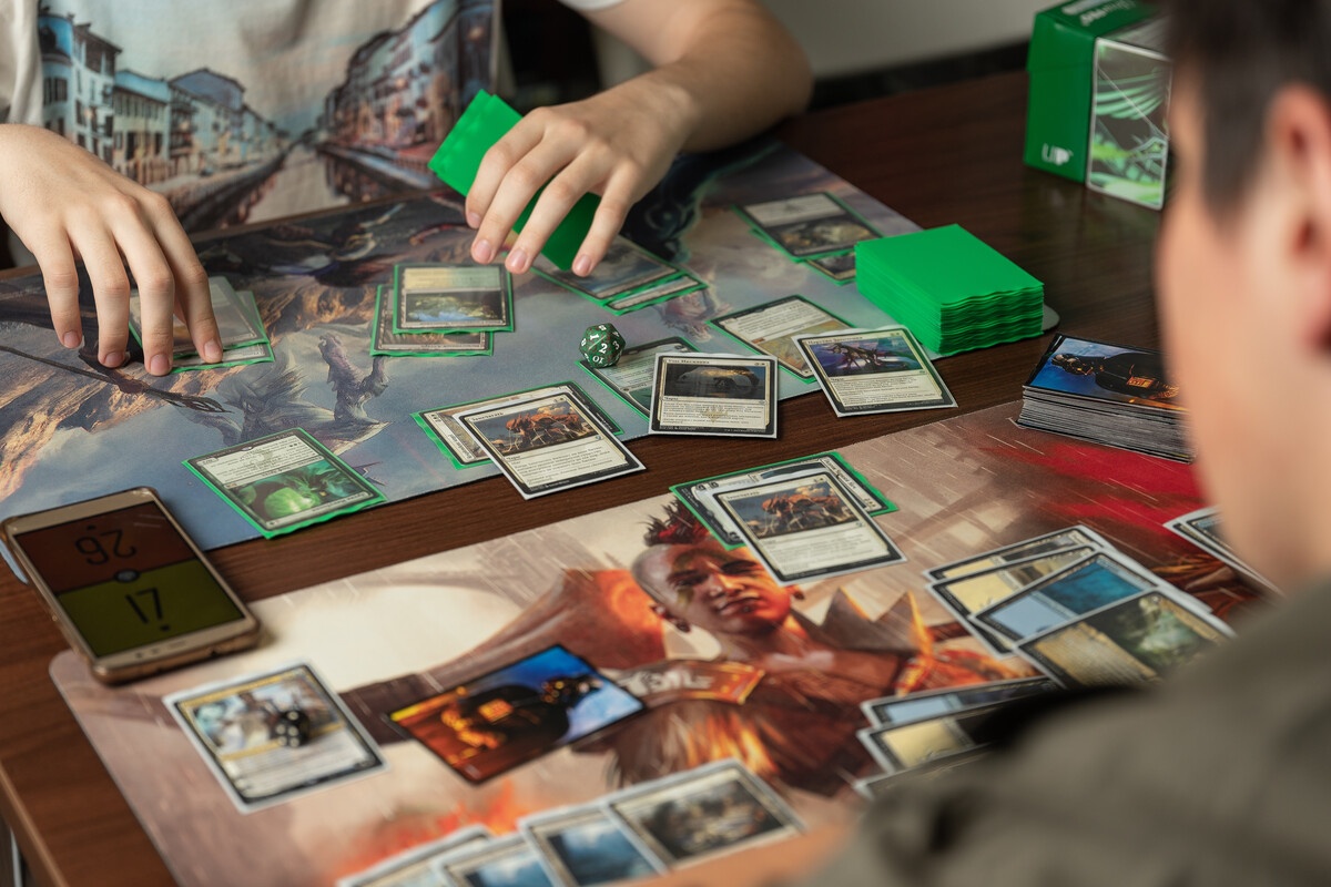 MTG gameplay overhead view showing a green deck with cards on a playmat