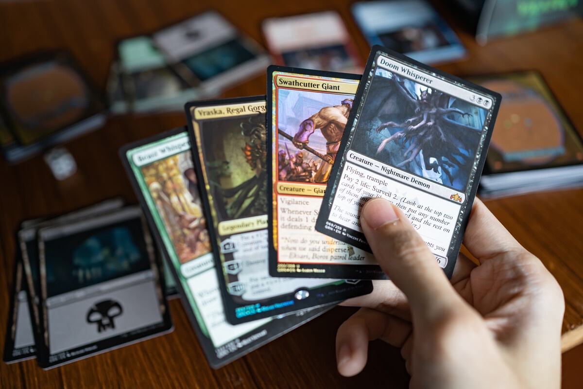 MTG hand holding a fan of cards showing Doom Whisperer and Swathcutter in closeup