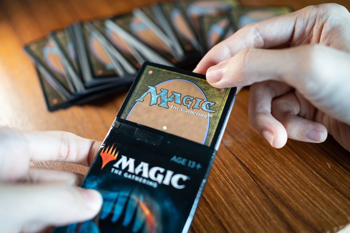 Hands opening a Magic the Gathering booster pack on a table
