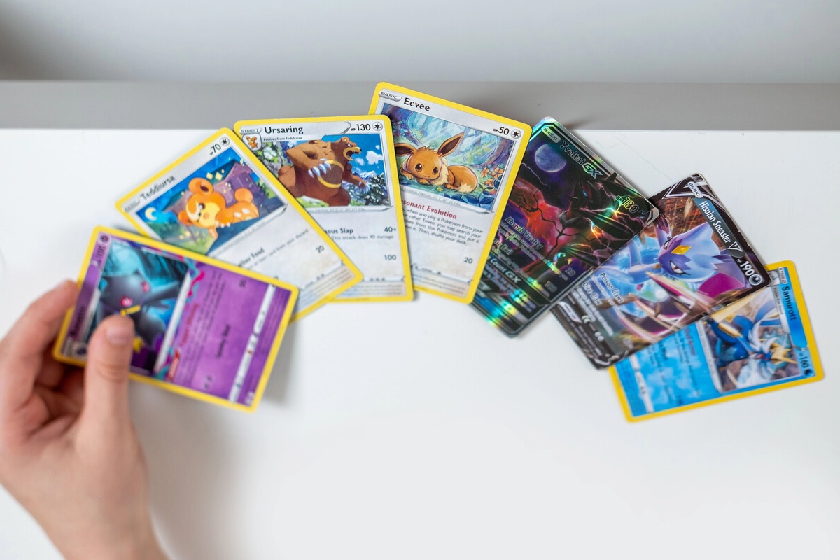 Pokemon cards being hand spread on a white table in casual setting