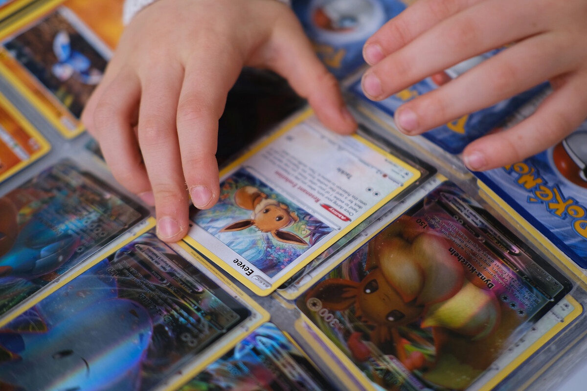 Child hands organizing Pokemon cards in a binder collection
