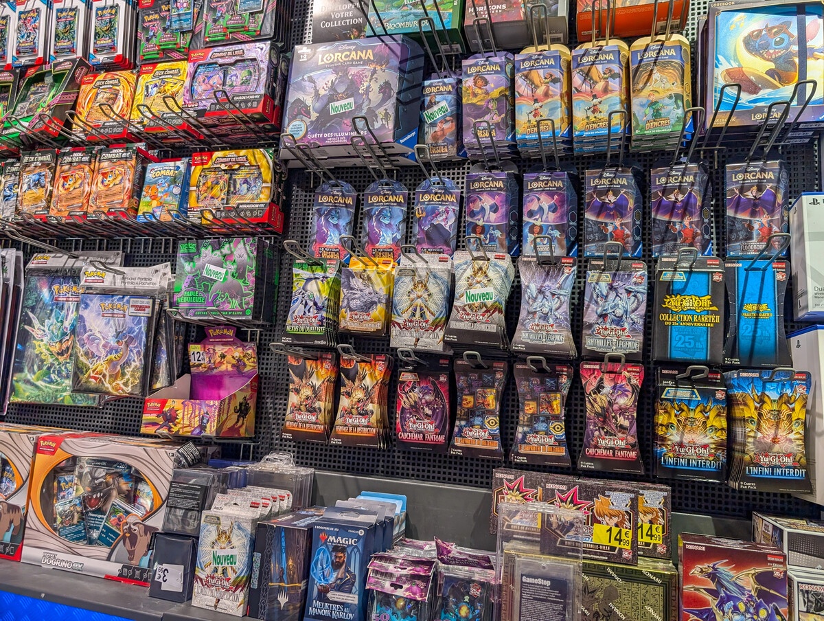 TCG retail display wall with Pokemon and Dragon Ball booster packs and sealed product