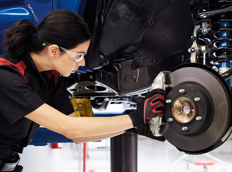 Basic Car Maintenance and Servicing Checklist | CMA's Toyota of Martinsburg | Female mechanic inspecting the brakes of a Toyota Tacoma