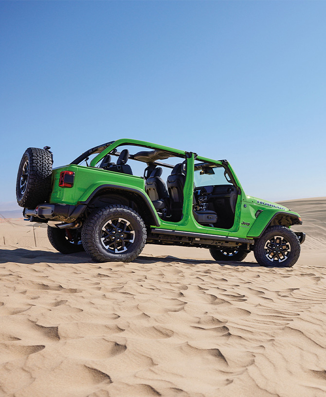 2025 Jeep Wrangler at Delaney CDJR of DuBois | Green 2025 Jeep Wrangler parked on top of some sand with no doors attached