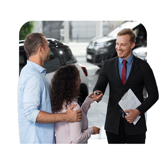 Defining GAP Insurance at Delaney CDJR of DuBois in DuBois, PA | Sales person in black suit handing over new car keys to couple