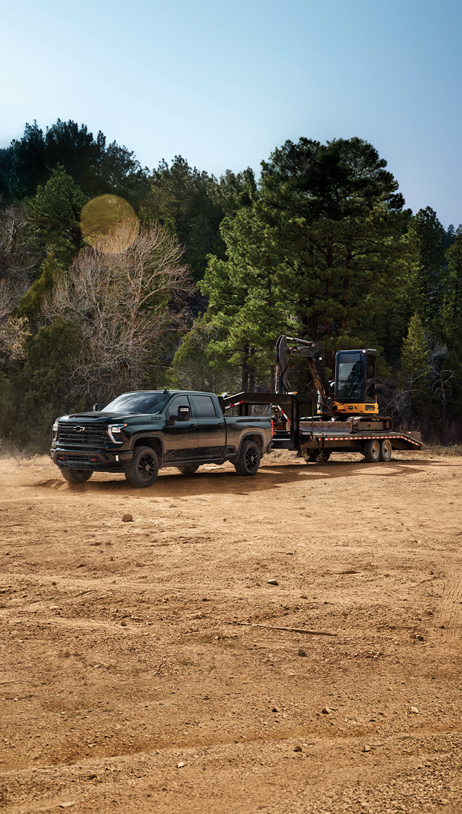 The 2025 Chevrolet Silverado 1500 at Delaney Chevrolet of Indiana | Black 2025 Chevy Silverado 1500 towing some construction equipment