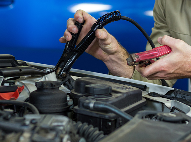 Everything You Need to Know about Your Car Battery at Delaney Chevrolet of Indiana | Person about to attached jumper cables to car battery 