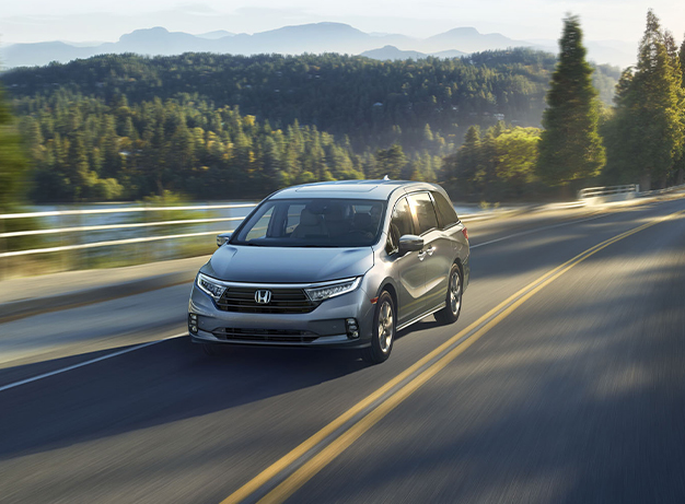 New 2025 Honda Odyssey at Delaney Honda | Front profile of a silver 2025 Honda Odyssey driving down an open road