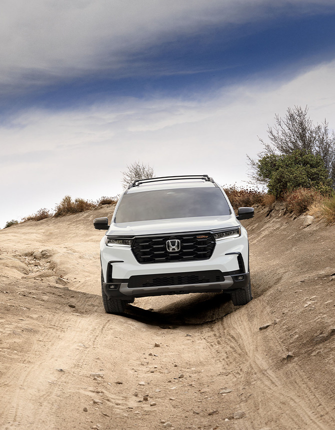 New 2025 Honda Pilot at Delaney Honda | White 2025 Honda Pilot driving down a hill New 2025 Honda Pilot at Delaney Honda | White 2025 Honda Pilot driving down a hill