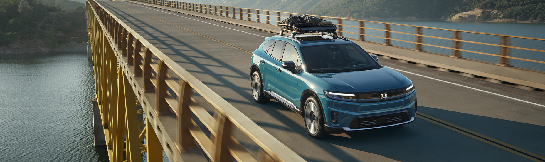 New 2025 Honda Prologue at Delaney Honda | Blue color 2025 Honda Prologue driving down a bridge while carrying cargo on the roof of the car