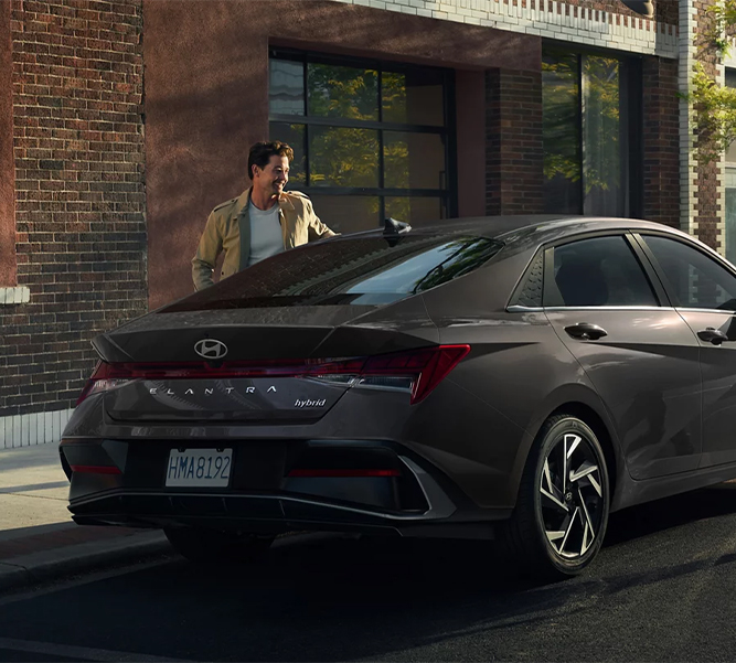  2026 Hyundai Elantra at Delaney Hyundai of Indiana | Man steeping out of his parked 2026 Hyundai Elantra Hybrid in the color dark grey