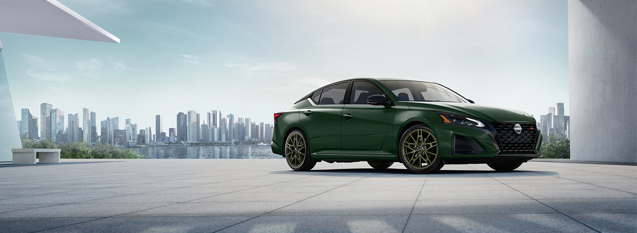 2025 Nissan Altima at Delaney Nissan of Greensburg | Dark green color 2025 Nissan Altima parked outside with views of some skyscrapers in the background