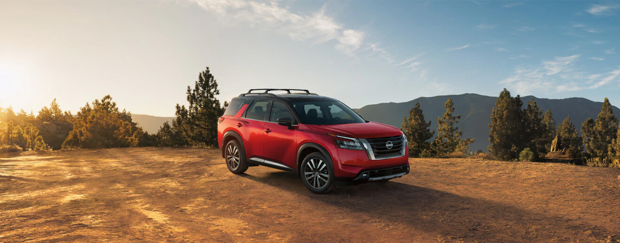 2025 Nissan Pathfinder at Delaney Nissan of Greensburg | Red 2025 Nissan Pathfinder parked on a hill with a view of the top of some mountains