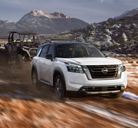2025 Nissan Pathfinder at Delaney Nissan of Greensburg | White 2025 Nissan Pathfinder towing a UTV on some trail around mountains