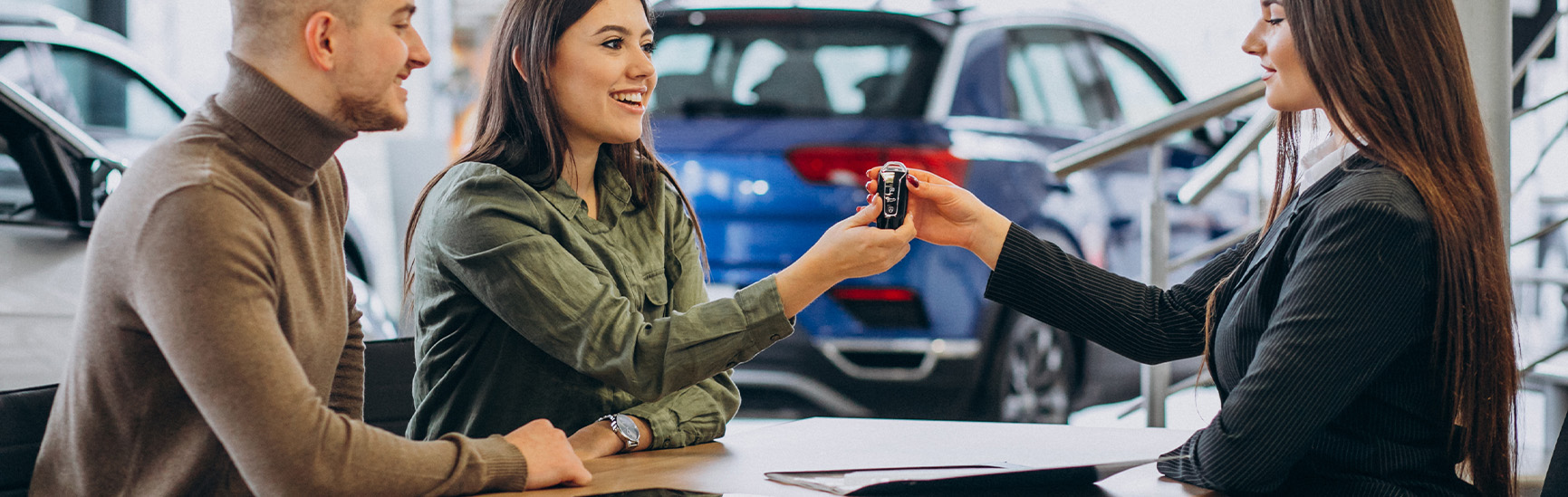 Why drivers should consider an extended warranty on their Nissan at Delaney Nissan of Greensburg | Sales person handing over new car keys to client inside of dealership