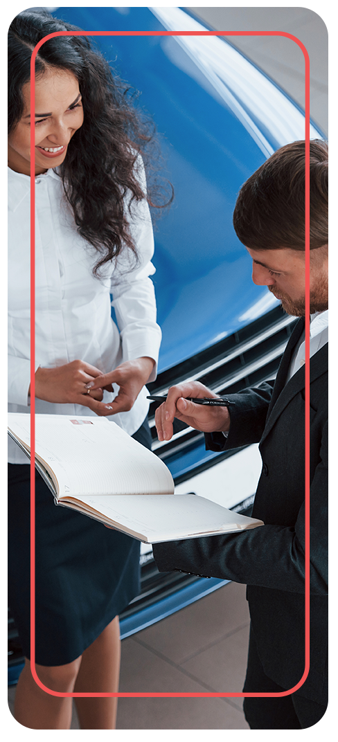 How to Prepare to Trade in Your Car |  Delaney Nissan of Greensburg in Greensburg, PA | woman in white shirt showing paperwork of her vehicle to sales person in black suit 