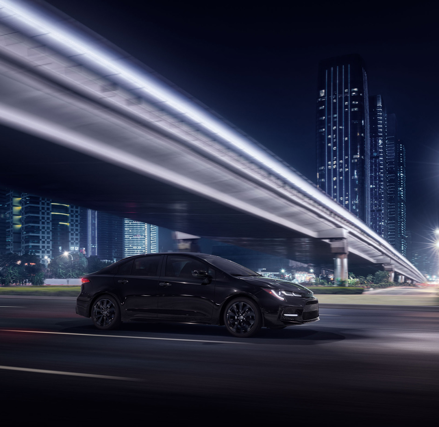 The New 2025 Toyota Corolla at Delaney Toyota of DuBois in DuBois, PA | Black 2025 Toyota Corolla driving past a city bridge