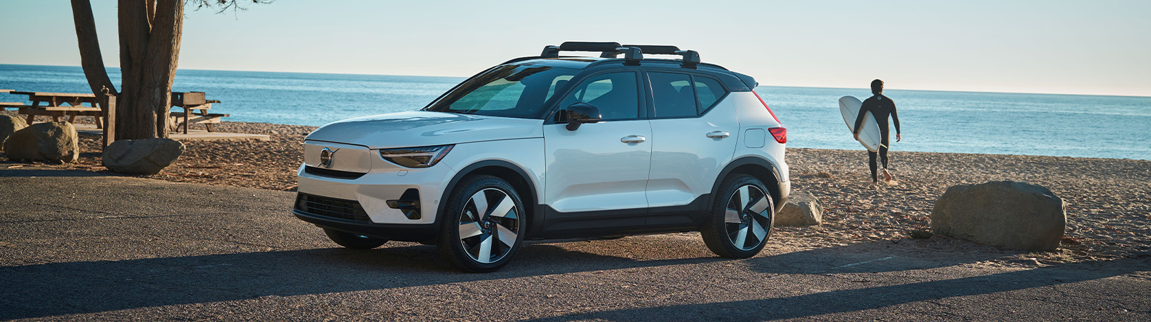 2026 Volvo XC40 | Man walking away from his parked 2026 Volvo XC40 while carrying his surfboard 