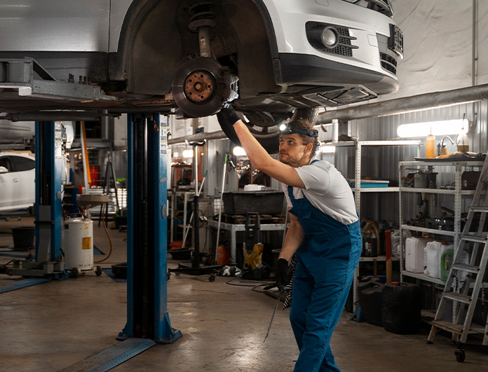 Check Engine Light Diagnostics at Lancaster Toyota | Mechanic working underneath a lifted car inside of a service shop