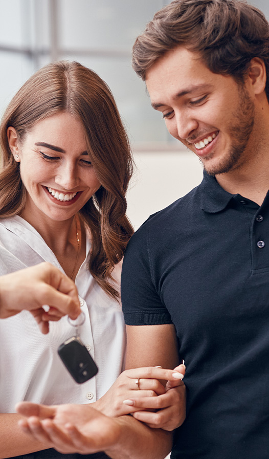 Buying New vs. Used. Learn more at Mechanicsville Toyota in Mechanicsville, VA | Person handing over new car keys to a happy couple
