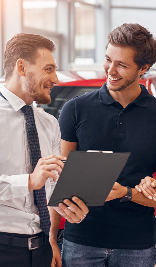 Buying New vs. Used. Learn more at Mechanicsville Toyota in Mechanicsville, VA | Sales representative showing a customer the car fax on his clipboard