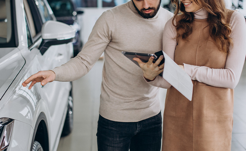 The Advantages of Buying a Car from a Dealership vs. a Private Seller. Learn more at Palmiero Toyota in Meadville, PA | Couple looking at Ipad together while standing in front of a new car