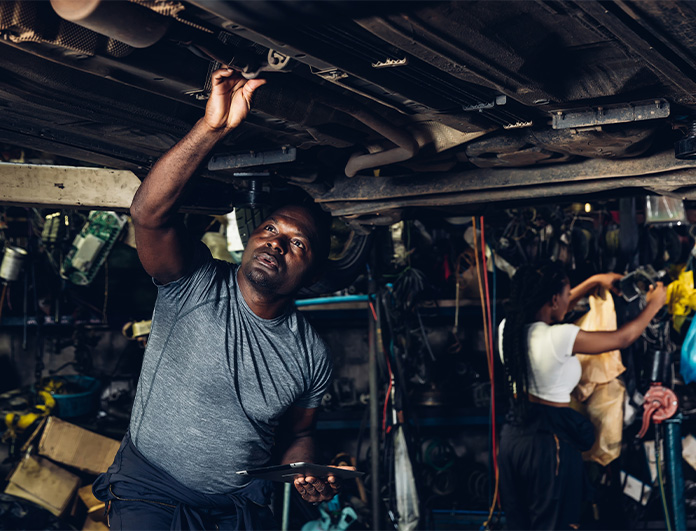 Check Engine Light Diagnostics at Palmiero Toyota | Mechanic working underneath a lifted car inside of a service shop