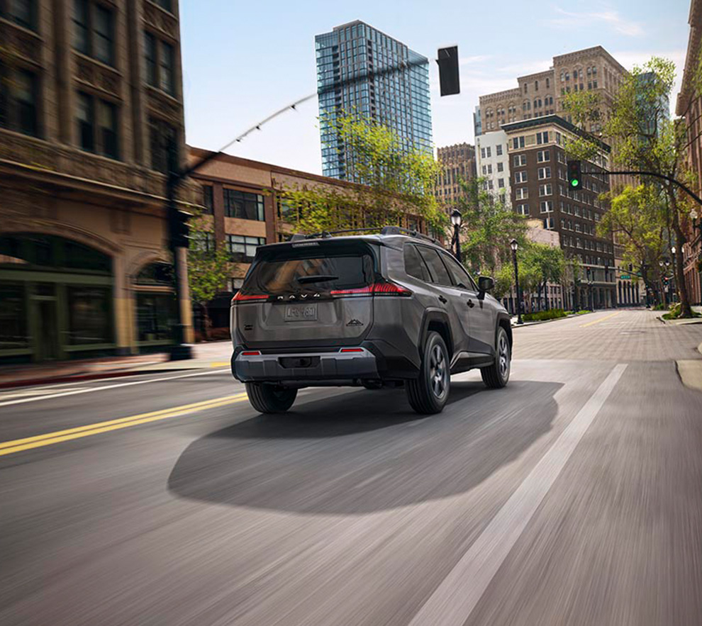 2026 Toyota RAV4 at Palmiero Toyota in Meadville, PA | Rear profile of a 2026 Toyota RAV4 driving down a city street