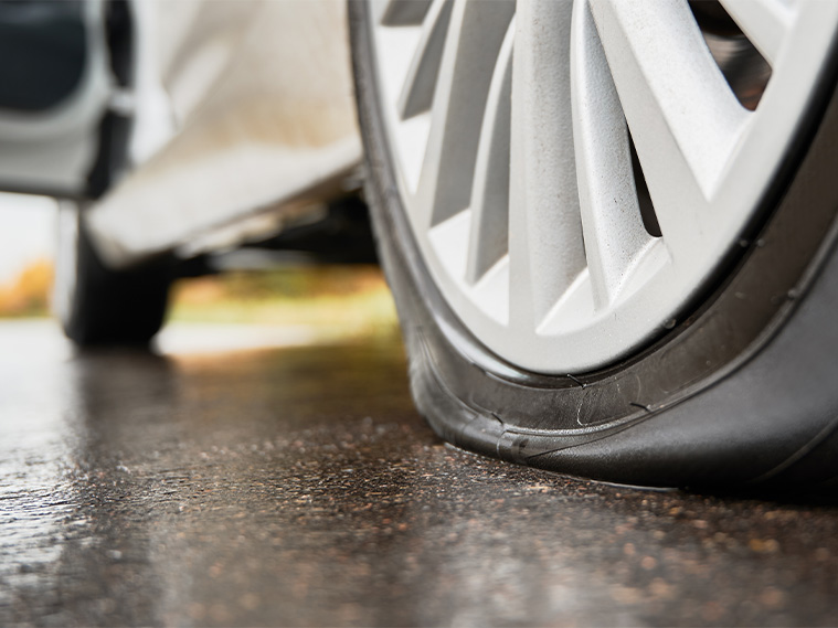 Why you should avoid potholes in York, PA | Close up of a flat tire caused by a pothole in the road