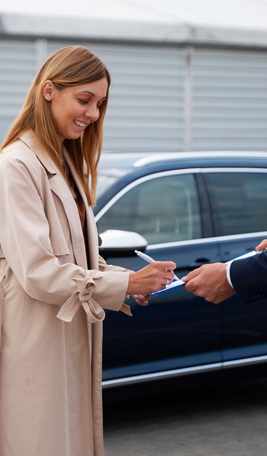 Buying New vs. Used. Learn more at Stetler DCJR in York, PA | Woman signing paperwork for her new used car in the background