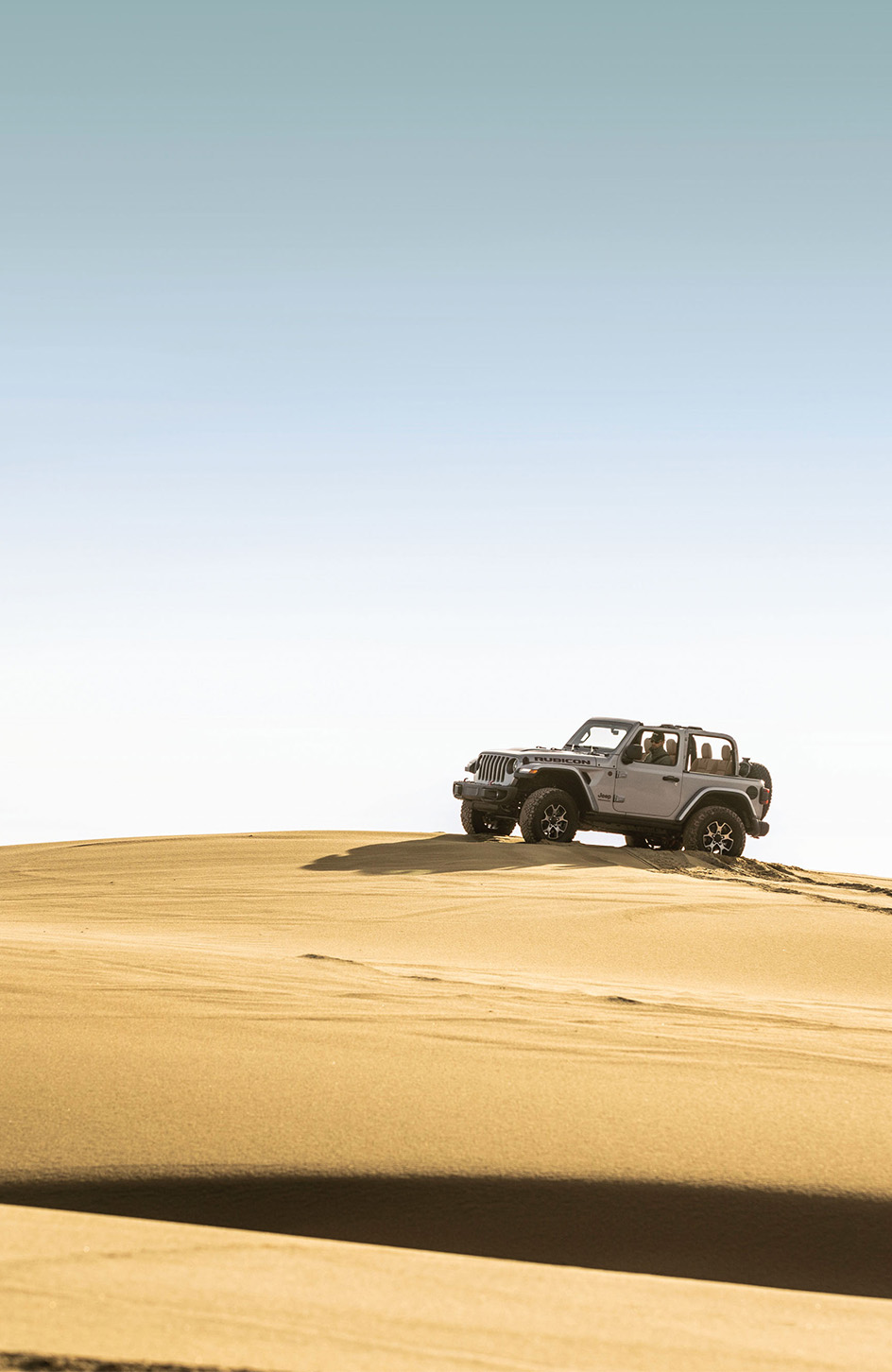 2026 Jeep Wrangler at CMA's CDJR of Martinsburg | Grey 2026 Jeep Wrangler 2-door driving up a hill of sand 2026 Jeep Wrangler at CMA's CDJR of Martinsburg | Grey 2026 Jeep Wrangler 2-door driving up a hill of sand