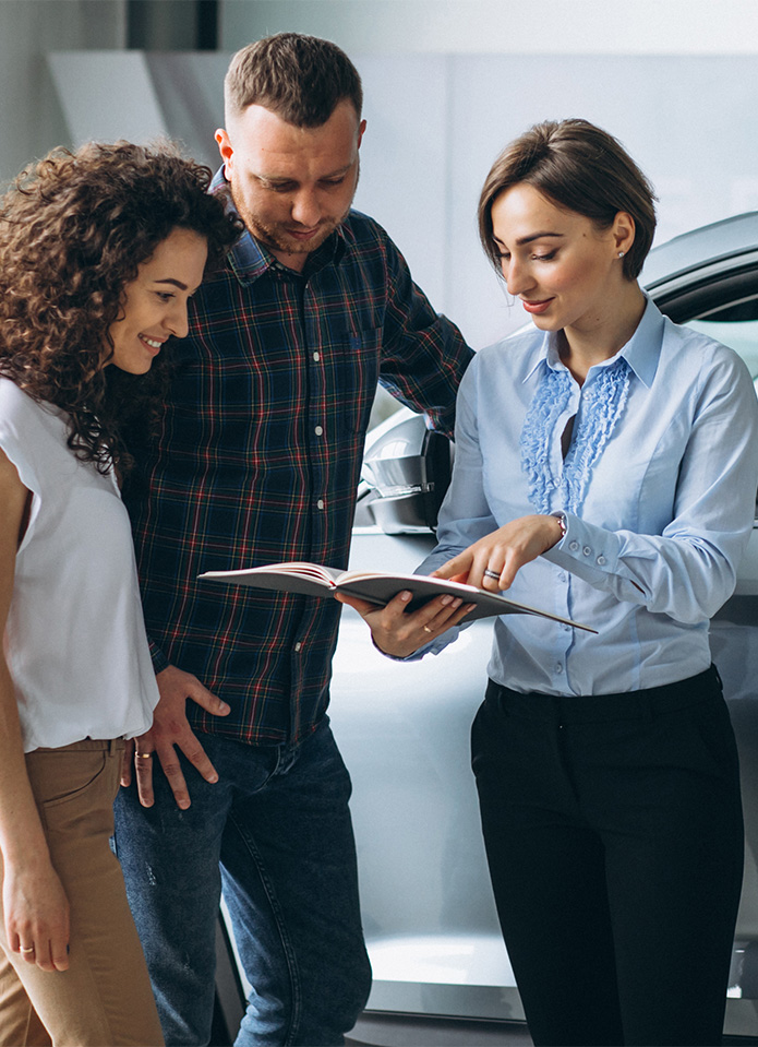 Federal Auto Loan Interest Tax Deduction At Delaney Chevrolet of Greensburg in Greensburg, PA | Sales associate in blue shirt showing customers a handbook on auto loans