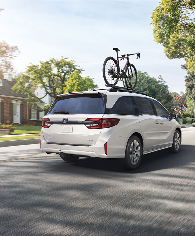 New 2026 Honda Odyssey at Delaney Honda | Rear profile of a white 2026 Honda Odyssey driving down the neighborhood