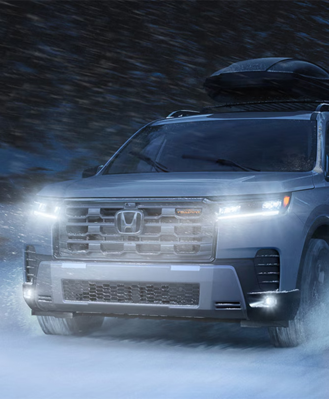 New 2026 Honda Pilot at Delaney Honda | Grey 2026 Honda Pilot driving in the snow with the headlights on New 2026 Honda Pilot at Delaney Honda | Grey 2026 Honda Pilot driving in the snow with the headlights on