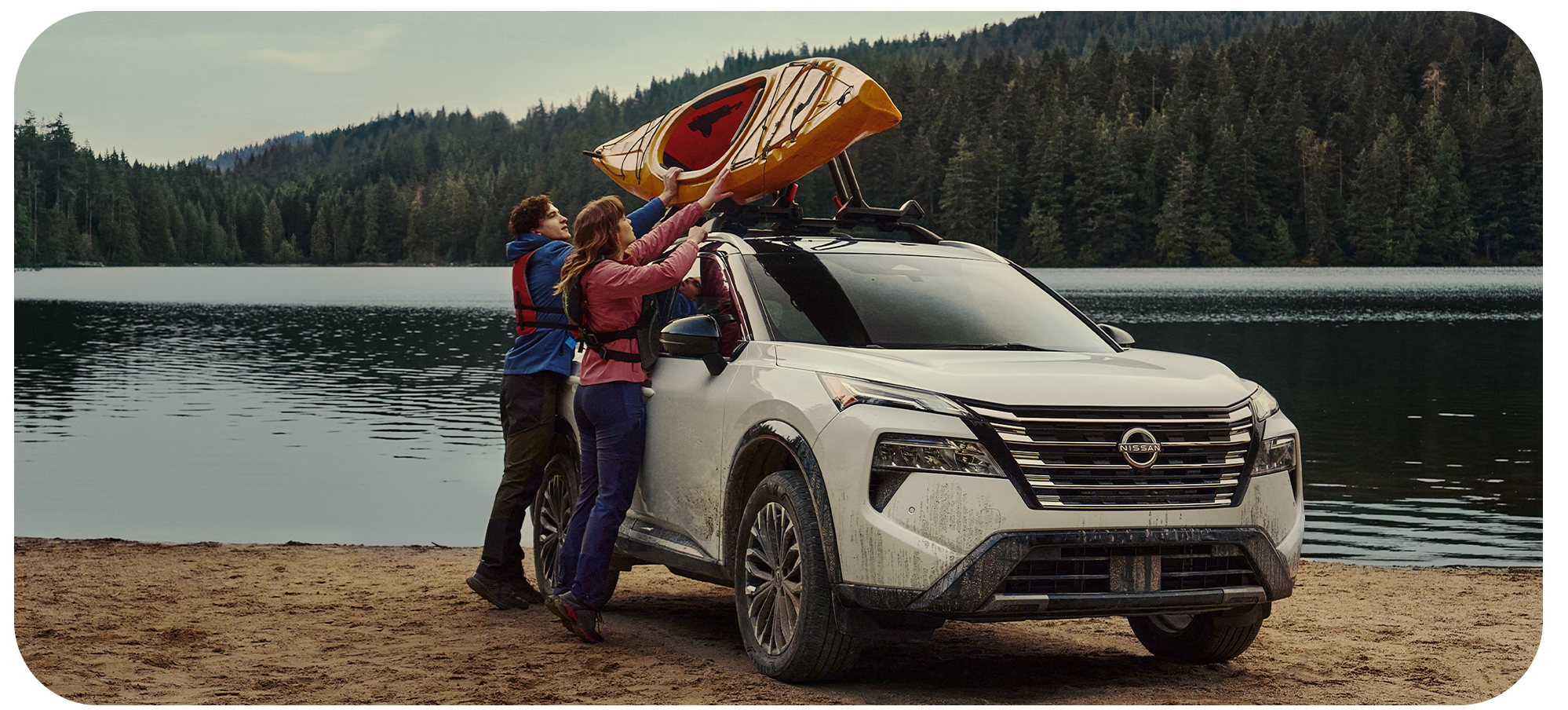 2026 Nissan Rogue vs. 2026 Honda CR-V vs. 2026 Toyota RAV4 at Delaney Nissan of Greensburg in Greensburg, PA | Couple bringing down a kayak that is on the roof rack of a 2026 Nissan Rogue