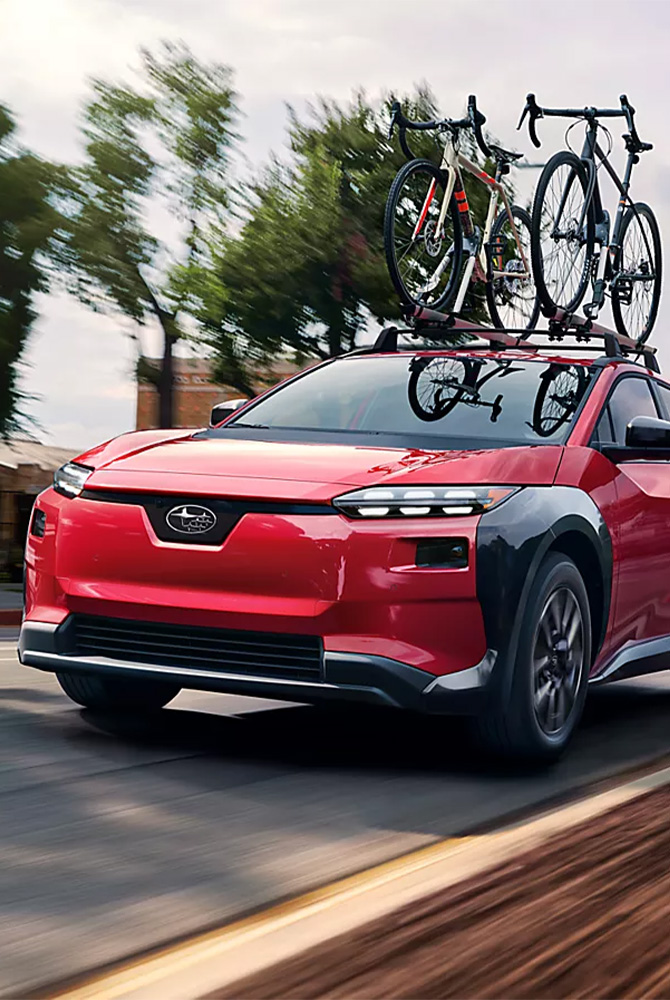 2026 Subaru Solterra at Delaney Subaru in Indiana, PA | Red 2026 Subaru Solterra driving down the street with bike on bike rack 2026 Subaru Solterra at Delaney Subaru in Indiana, PA | Red 2026 Subaru Solterra driving down the street with bike on bike rack