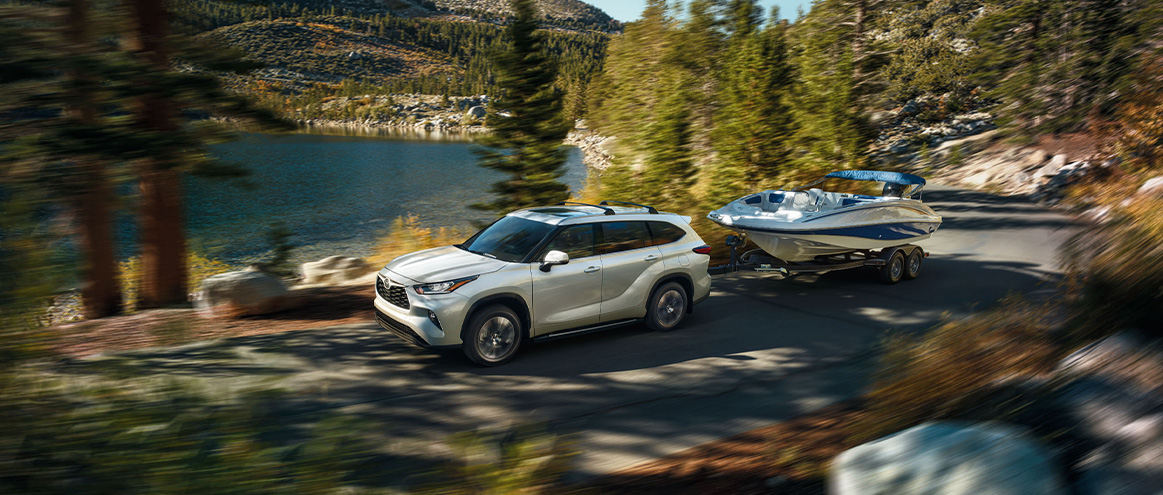The New 2026 Toyota Highlander and Grand Highlanders at Delaney Toyota of DuBois | White 2026 Toyota Highlander towing a small boat on the road The New 2026 Toyota Highlander and Grand Highlanders at Delaney Toyota of DuBois | White 2026 Toyota Highlander towing a small boat on the road