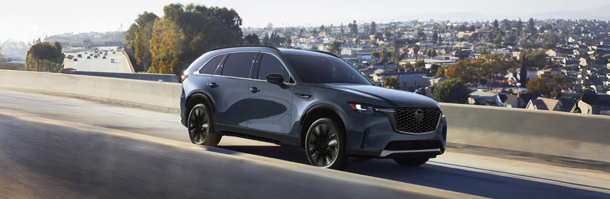 2026 Mazda CX-90 at Lancaster Mazda in East Petersburg, PA | Dark blue 2026 Mazda CX-90 driving down the road 2026 Mazda CX-90 at Lancaster Mazda in East Petersburg, PA | Dark blue 2026 Mazda CX-90 driving down the road