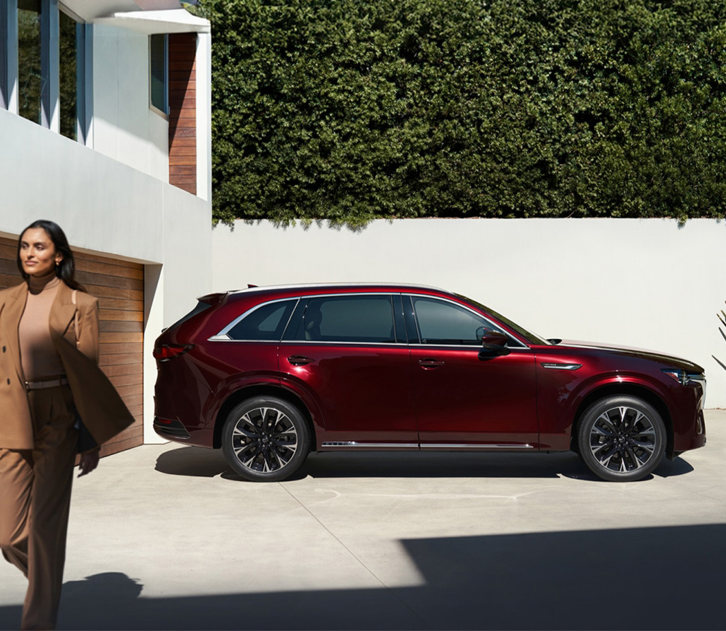 2026 Mazda CX-90 at Lancaster Mazda in East Petersburg, PA | Woman walking away from her parked 2026 Mazda CX-90 in the color burgundy 2026 Mazda CX-90 at Lancaster Mazda in East Petersburg, PA | Woman walking away from her parked 2026 Mazda CX-90 in the color burgundy