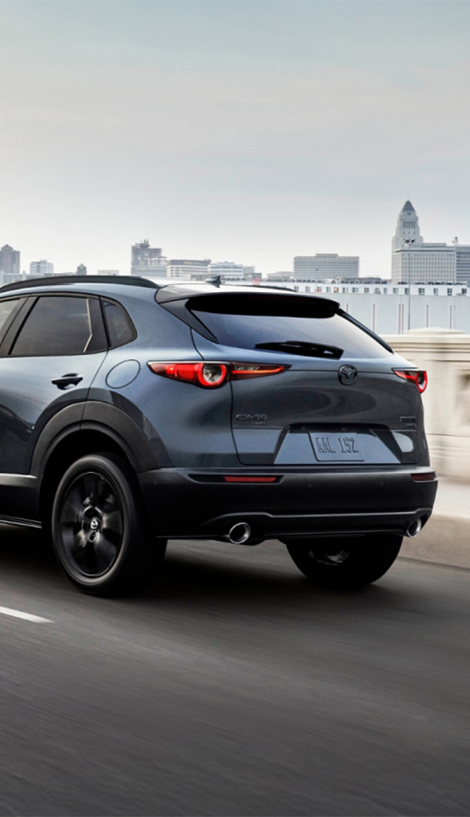 2026 Mazda CX-30 at Lancaster Mazda | Rear profile of a 2026 Mazda CX-30 driving on a city bridge 2026 Mazda CX-30 at Lancaster Mazda | Rear profile of a 2026 Mazda CX-30 driving on a city bridge