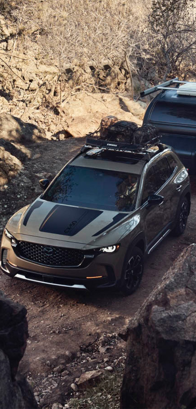2026 Mazda CX-50 at Lancaster Mazda | 2026 Mazda CX-50 towing a trailer in the middle of an off road trail 2026 Mazda CX-50 at Lancaster Mazda | 2026 Mazda CX-50 towing a trailer in the middle of an off road trail