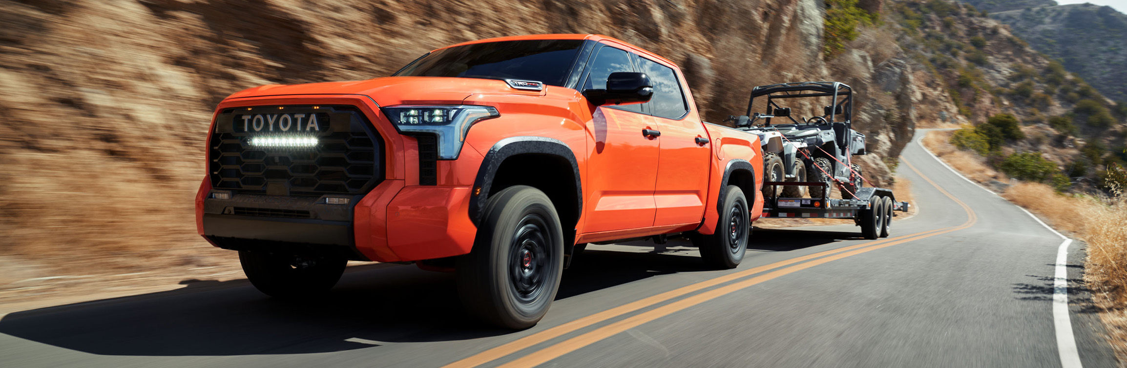 The New 2026 Toyota Tundra at Lancaster Toyota in East Petersburg, PA | Orange color 2026 Toyota Tundra towing a ATV up a hill The New 2026 Toyota Tundra at Lancaster Toyota in East Petersburg, PA | Orange color 2026 Toyota Tundra towing a ATV up a hill