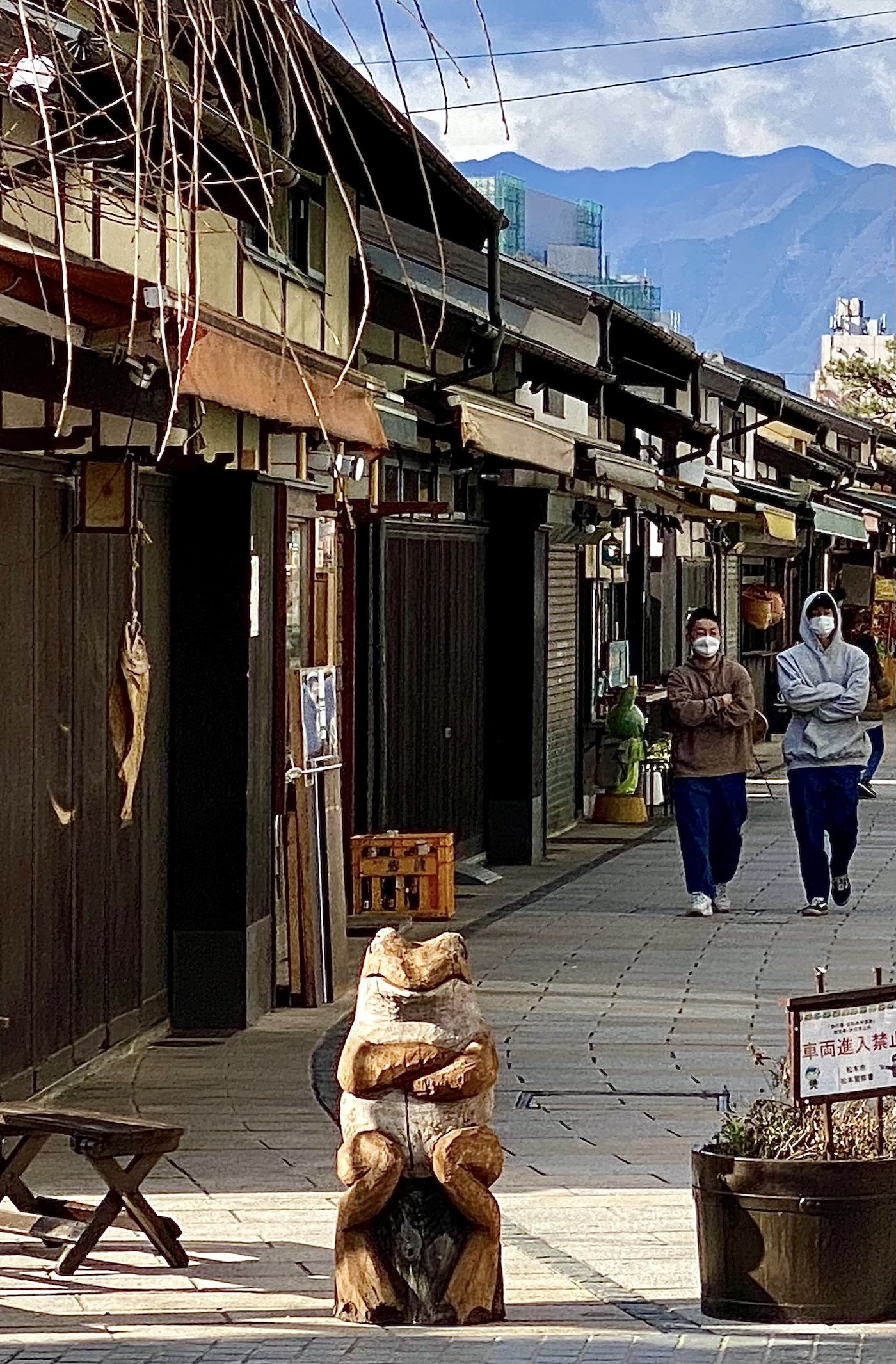 Two people walking with arms folded matching the toad statue ahead of them