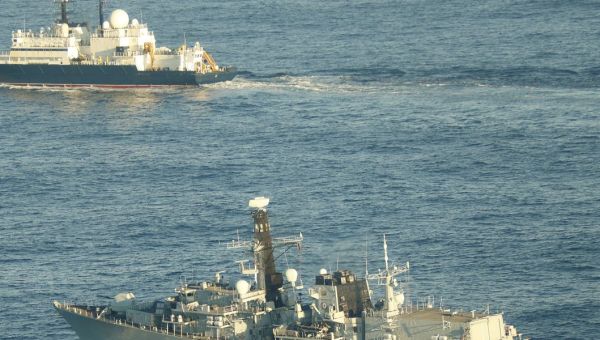 A British submarine secretly tracking a Russian spy ship hanging around undersea cables suddenly surfaced close to send a message, UK says