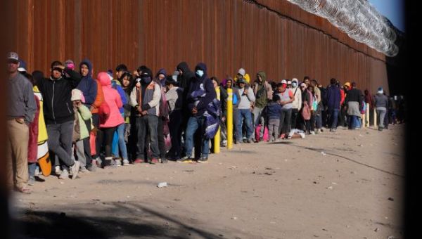 Hundreds of migrants line up a mile down the border from National Guard Troops