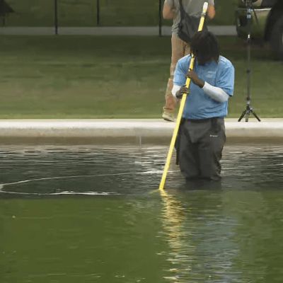 Crews continue work to clean green algae from the newly repainted Reflecting Pool