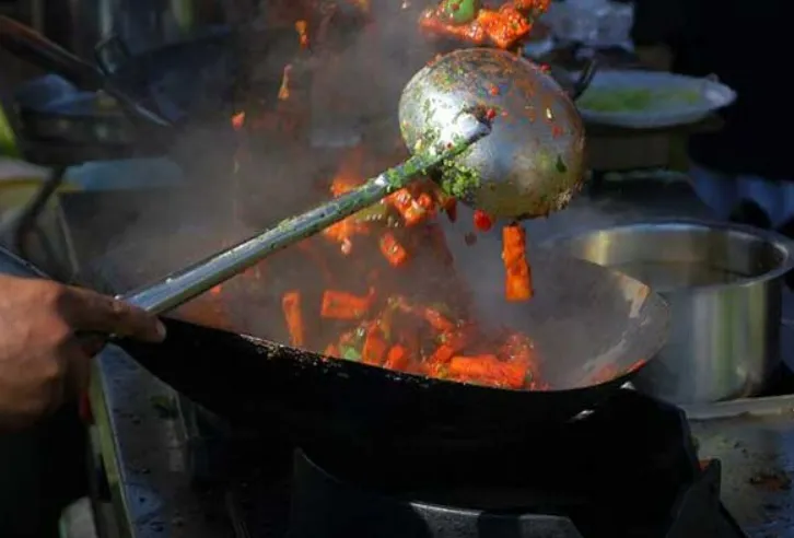 Vietnamese chef performing xào stir-frying technique in traditional wok